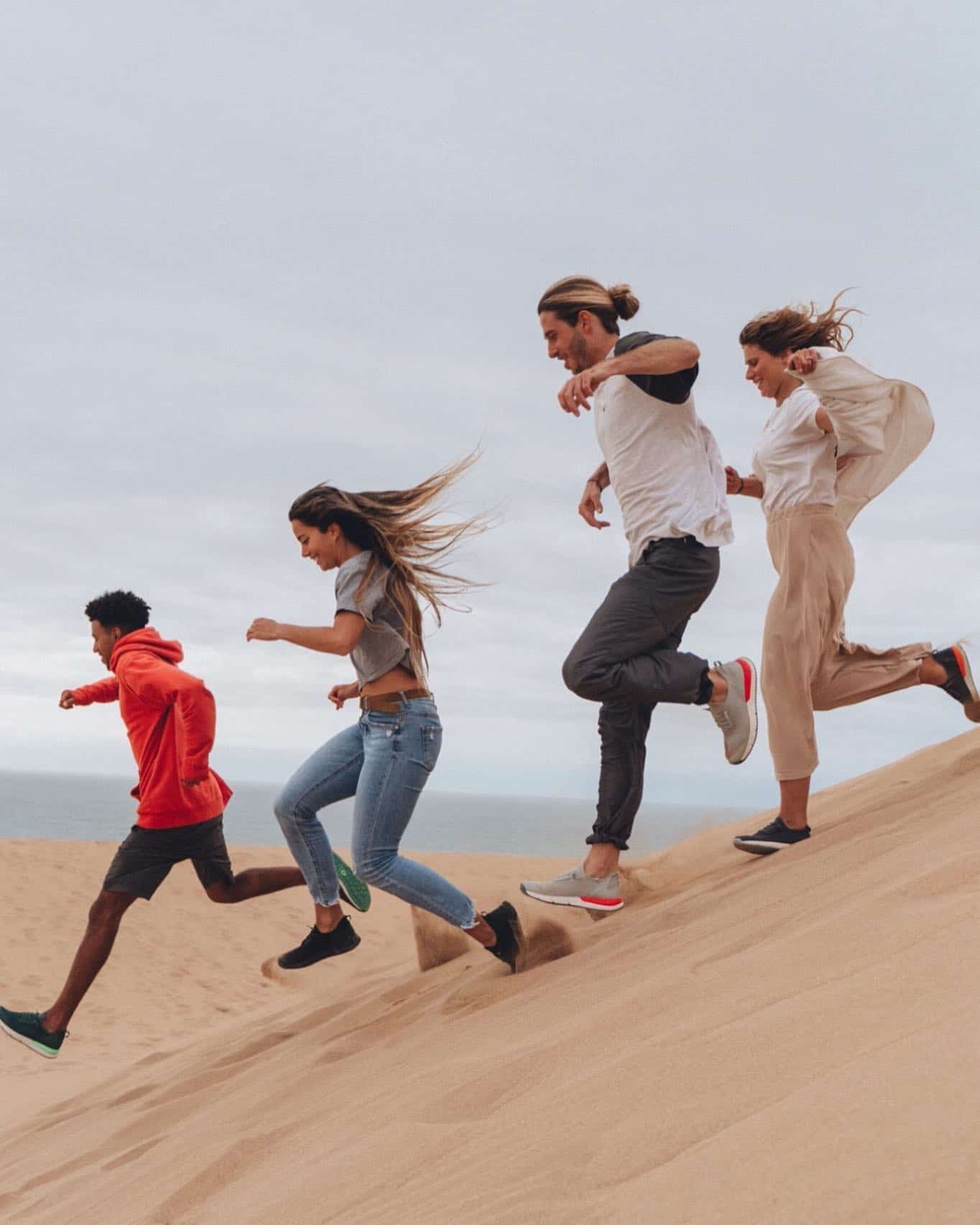 a group of friends running down a sand dune